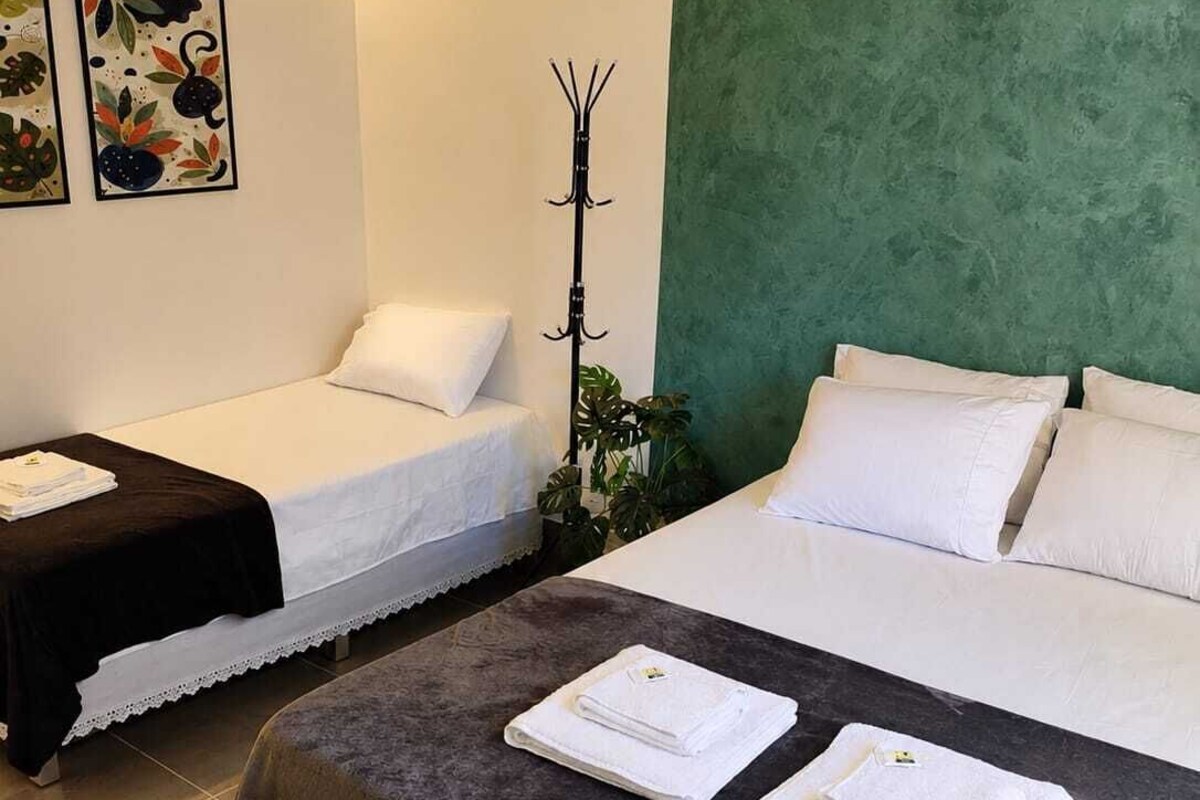 A hotel room with two beds, a bench, and a coat rack.