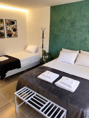 A hotel room with two beds, a bench, and a coat rack. - Gyn Suites (Goiania)
