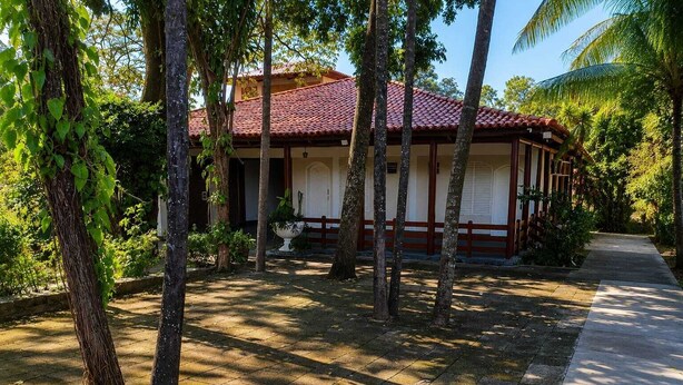 A traditional building with a tiled roof, surrounded by trees and a paved walkway. - Gyn Suites (Goiania)