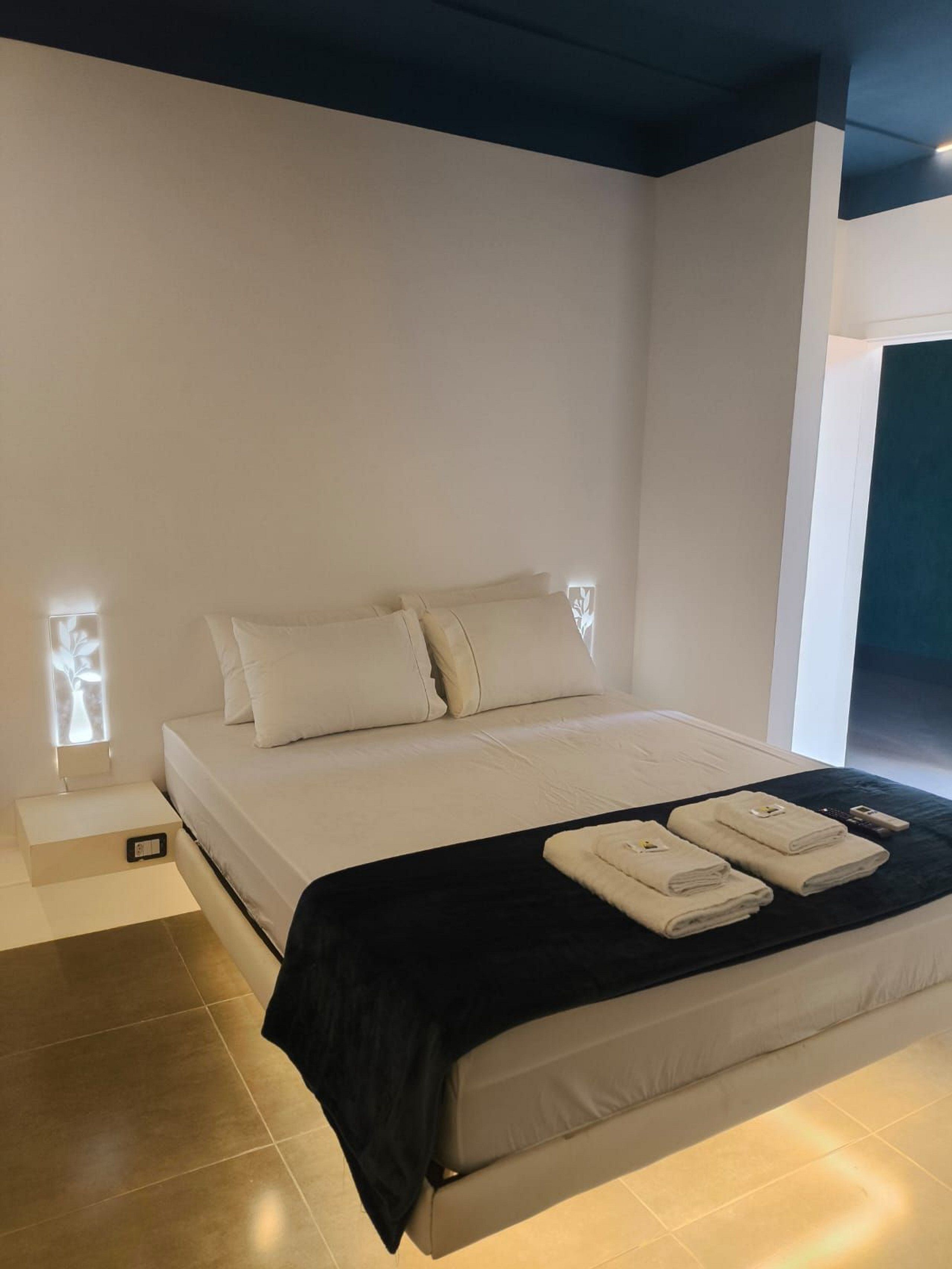 Un dormitorio moderno con una cama grande, una mesita de noche y un ventanal con persianas.