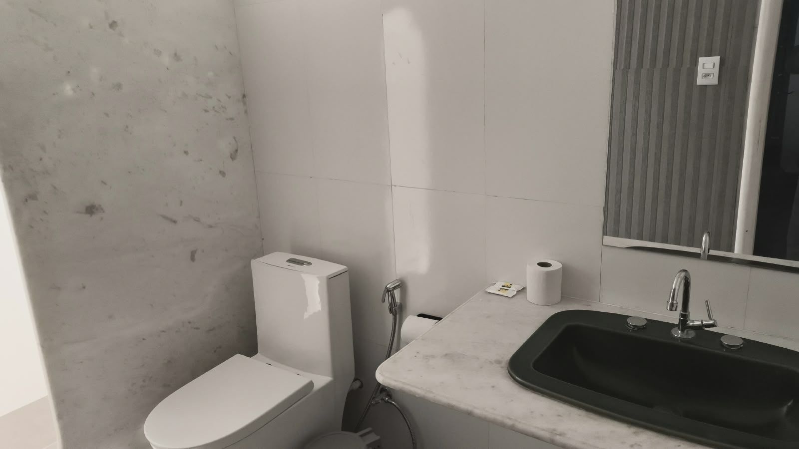 A small bathroom with a toilet, a sink, and a mirror.