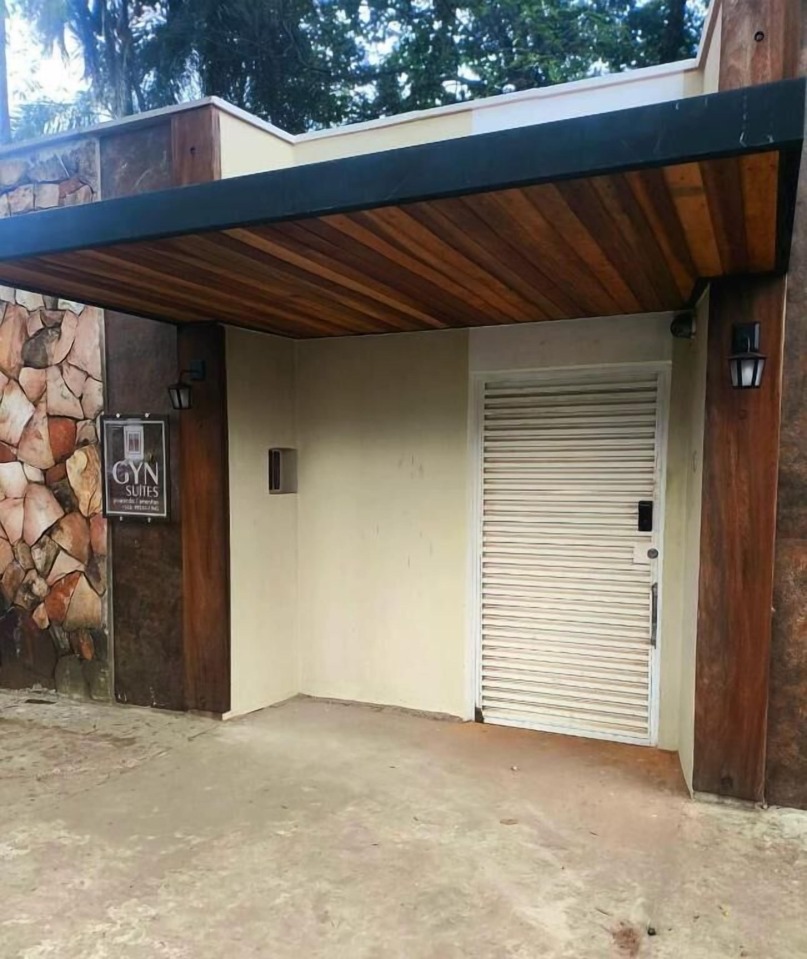 A building entrance with a stone wall, a wooden ceiling, and a closed garage door.