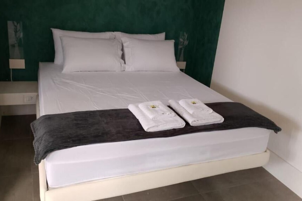 A neatly made bed with white linens and two towels on the bed.