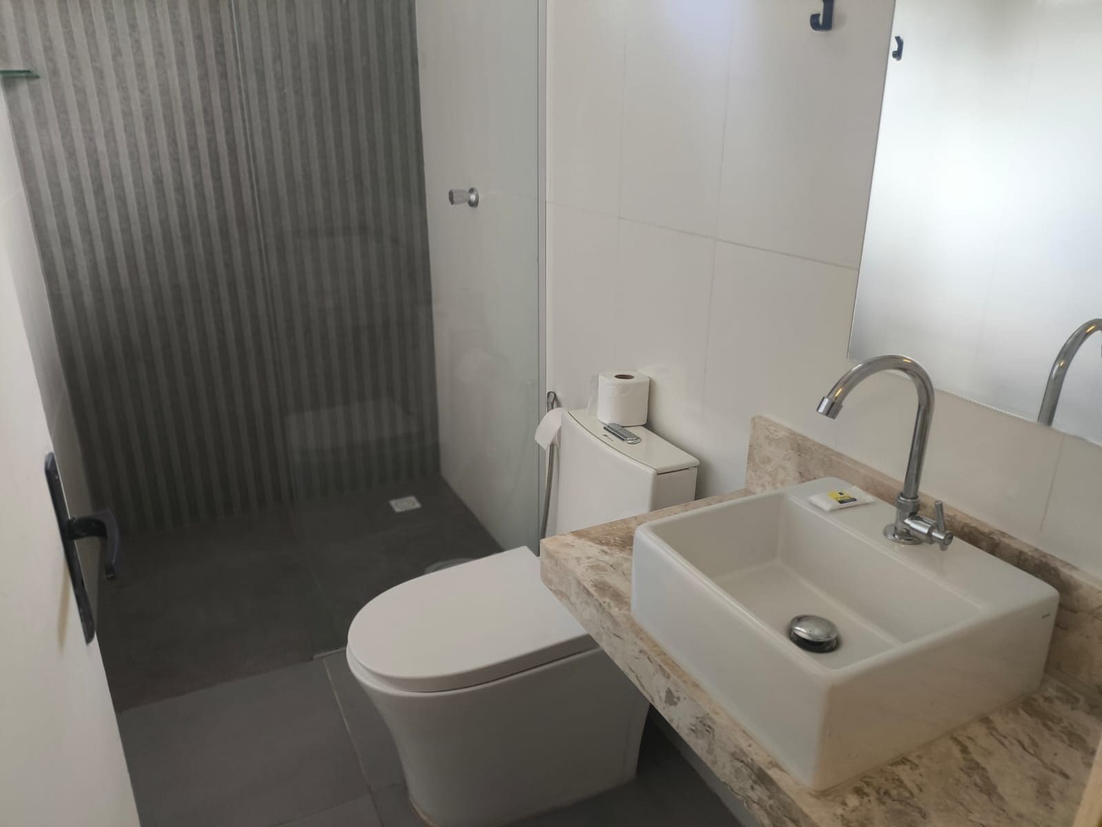 Uma casa de banho moderna com sanita, lavatório e chuveiro.
