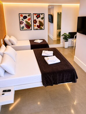 A hotel room with two beds, a TV, a plant, and artwork on the wall. - Gyn Suites (Goiania)