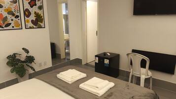 Habitació d'hotel amb un llit, una taula, una cadira, una televisió i obra d'art a la paret.