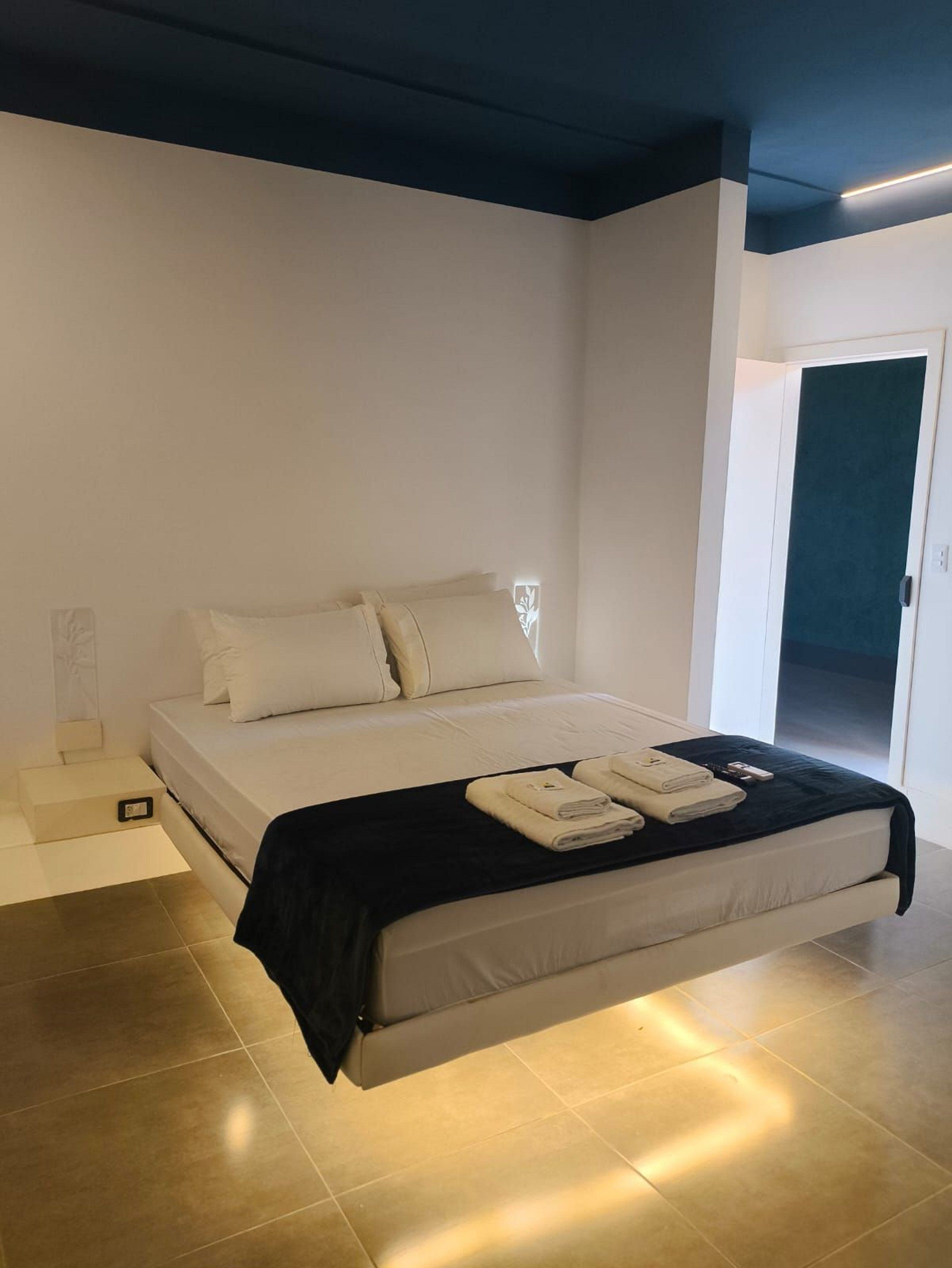 A modern bedroom with a bed, bedside table, and a door.
