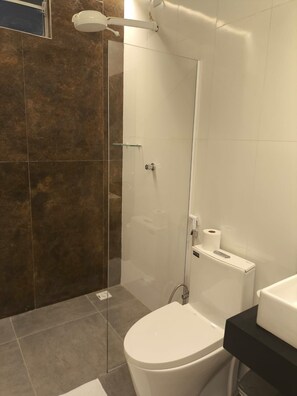 A modern bathroom with a glass-enclosed shower, a toilet, and a sink. - Gyn Suites Sul (Goiania)