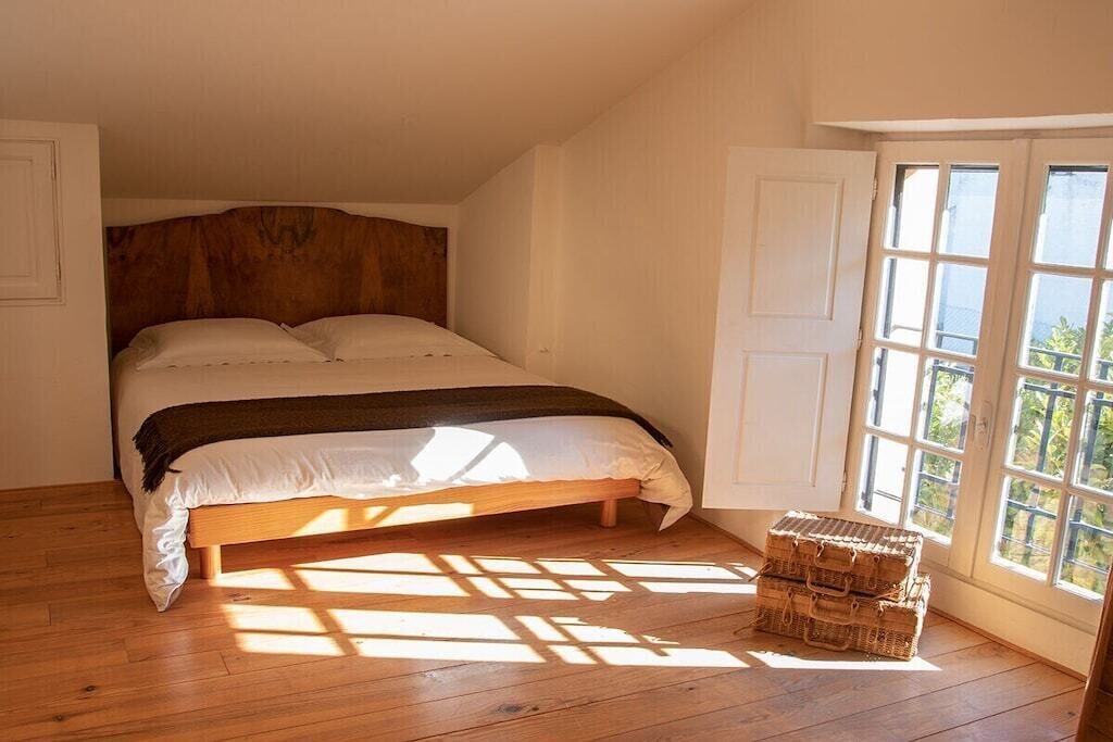 A bedroom with a wooden bed, a window with a view, and a small wooden chest.