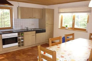 Keittiössä on liesi, uuni, pesuallas ja kaappeja. Siellä on myös ruokapöytä tuoleineen ja ikkuna, josta on näkymä puita kohti.