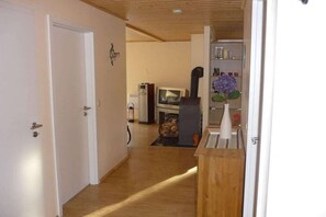 Un couloir avec un plancher en bois, une porte blanche et une petite structure en bois sur la droite.