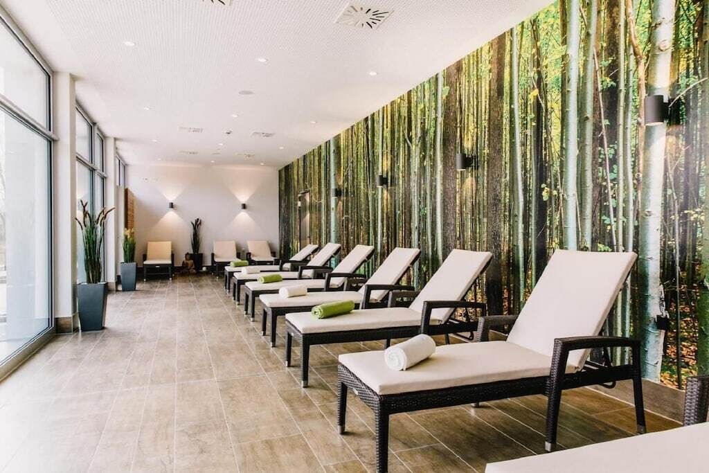 Een moderne spa-ruimte met rijen comfortabele stoelen en een wand vol verticale beplanting.