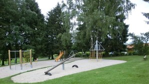 Une aire de jeux dotée de diverses structures ludiques et d’un bac à sable.