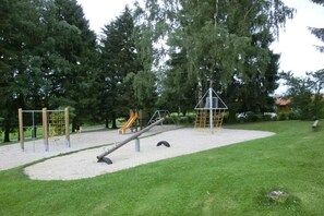 Ein Spielplatz mit verschiedenen Spielgeräten und einem Sandkasten.