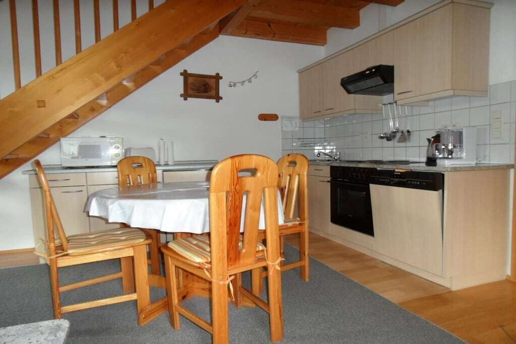 Une cuisine équipée de chaises en bois, d’une table à manger, d’un four à micro-ondes et d’un lave-vaisselle.