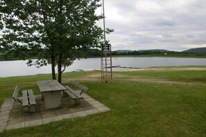 Ein Picknicktisch mit Bänken, eine Metallleiter und eine Wiese in der Nähe von Wasser.