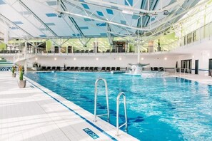 Une piscine intérieure à l’eau claire, dotée d’un plongeoir et d’un escalier menant à un niveau supérieur.