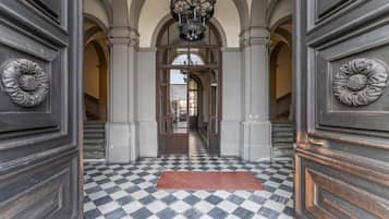 Un couloir doté d’un sol à carreaux, d’arcades et d’un lustre.