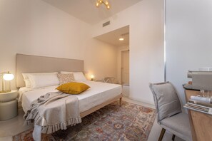A modern bedroom with a bed, bedside lamps, a chair, and a desk with a coffee machine. - Ecomarina (LIVORNO)