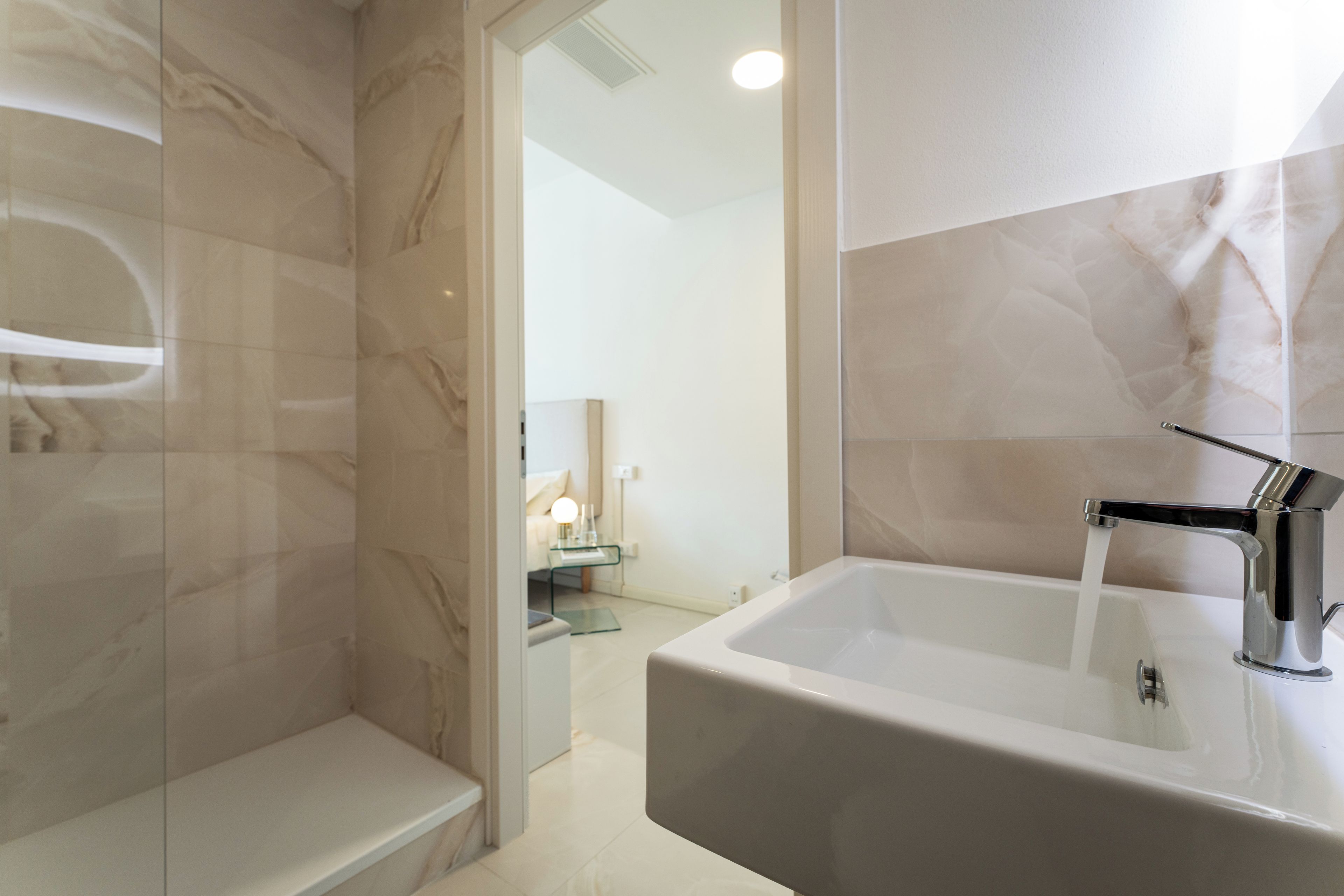 A bathroom with a large white sink, a chrome faucet, and a glass shower enclosure.