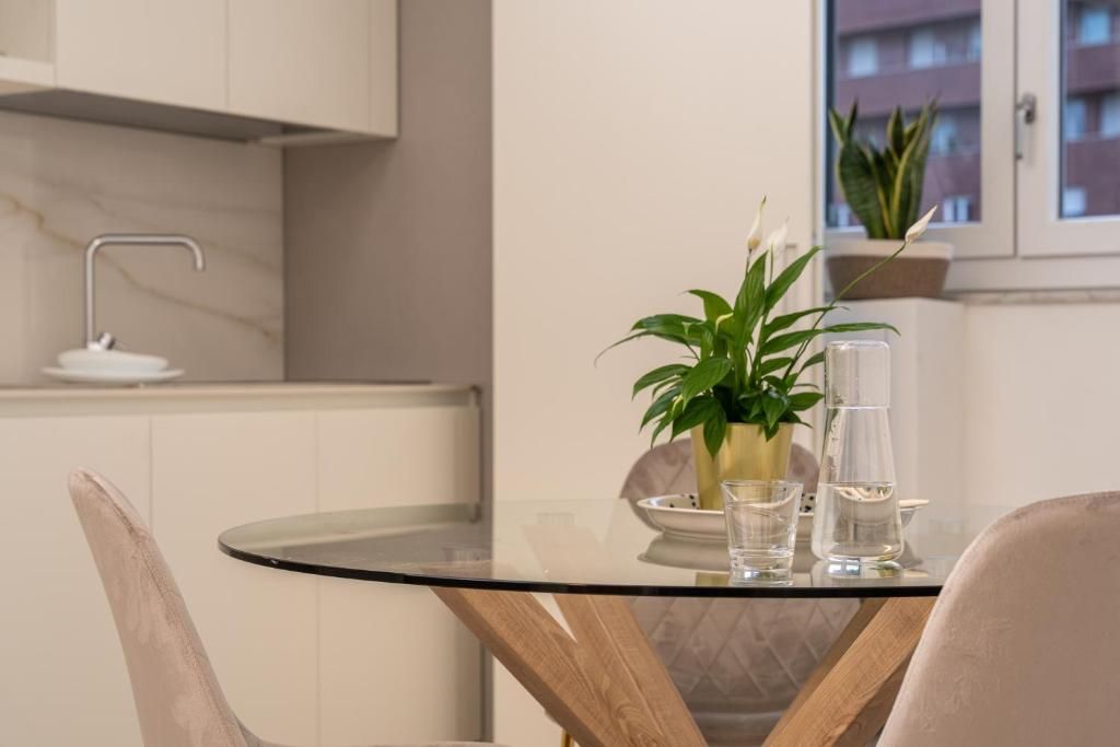 A modern kitchen with a glass table, a potted plant, and a water dispenser.