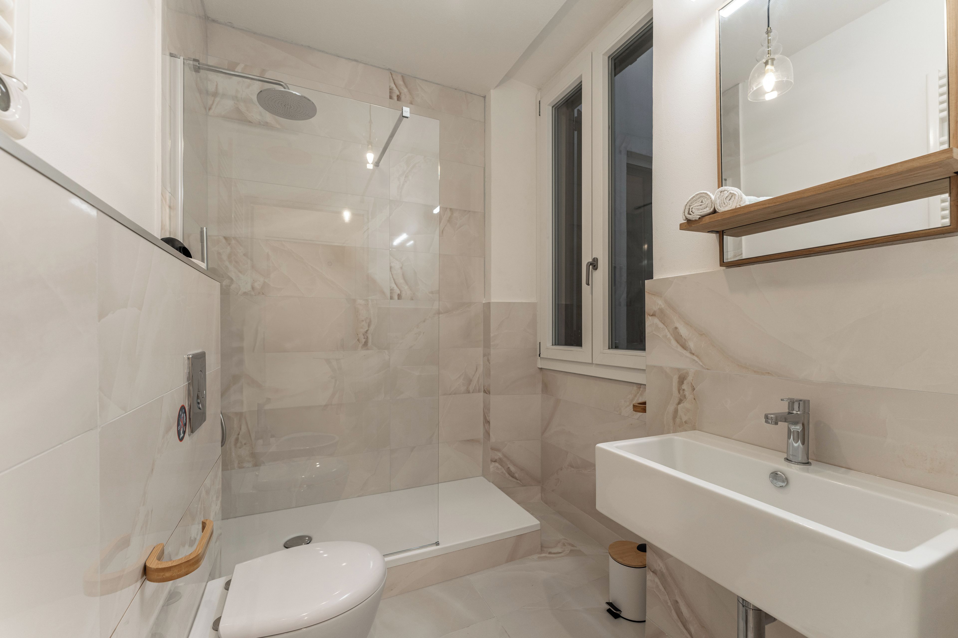 Et badeværelse med brusebad, toilet og håndvask.