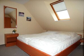 Ein Schlafzimmer mit einem Einzelbett, einem Nachttisch, einem Spiegel und einem Fenster.
