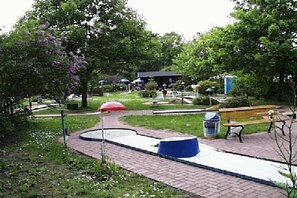 Ein Park mit einem gepflasterten Weg, Bänken und einem Spielplatz.