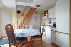 Ein Essbereich mit Tisch und Stühlen, eine Küche mit Schränken und Geräten sowie eine Treppe.