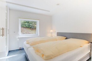 Een slaapkamer met een bed, een raam en een lamp.
