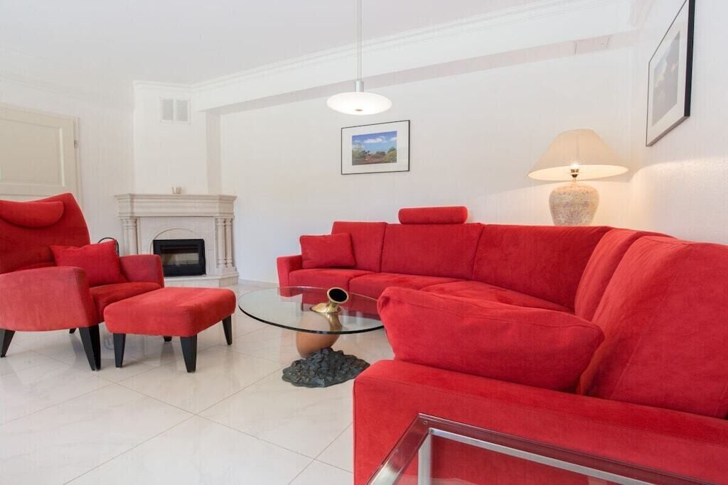 Un salon avec un canapé rouge, une table basse en verre et une cheminée.