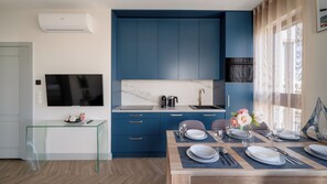 A modern kitchen with blue cabinets, a marble backsplash, and a dining area set for six with a glass table. - Apartamenty Sun & Snow Solmarina (Gdańsk)