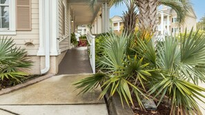 A covered porch with a concrete pathway leading to a house. - Myrtle Beach | Beach Escape | Pool & Boardwalk | Hotel (Myrtle Beach)