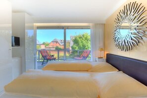 Ein Hotelzimmer mit einem großen Bett, einem Fernseher, einem Balkon mit Stühlen und einer dekorativen Wandgestaltung.