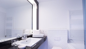 Uma casa de banho moderna com um espelho grande, lavatório branco e sanita.