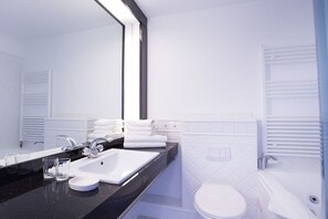 Ein modernes Badezimmer mit großem Spiegel, weißem Waschbecken und Toilette.