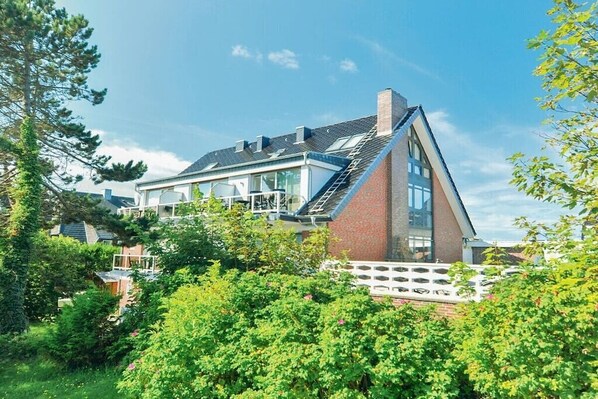 Ein modernes Haus mit Satteldach, großen Fenstern und einer Ziegelaußenwand.