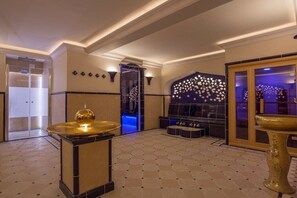 Eine Empfangshalle mit Schachbrettboden, einer goldenen Dekorationsschale, einer Sitzecke mit schwarzem Sofa und einer Wand mit Sternenmuster.