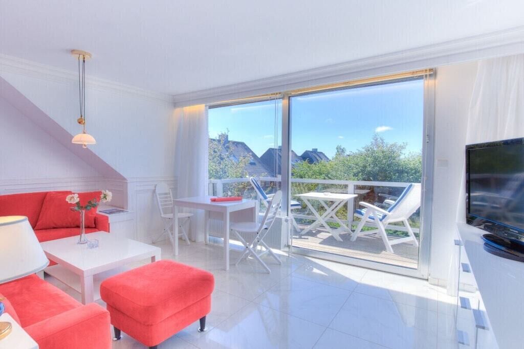 Un salon moderne avec un canapé rouge, une table basse blanche et un téléviseur.