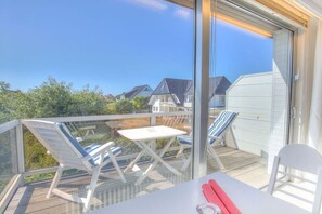 A balcony with a table and chairs, overlooking a residential area. - Holiday apartment in Sylt with 1 bedroom (Wenningstedt)