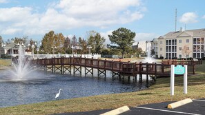 Ein Park mit einer Holzbrücke über dem Wasser, einem Brunnen und einem Schild für Kurzparkzonen.