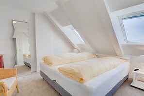 Une chambre moderne avec un plafond en pente, un grand lit, une table de chevet et une chaise.