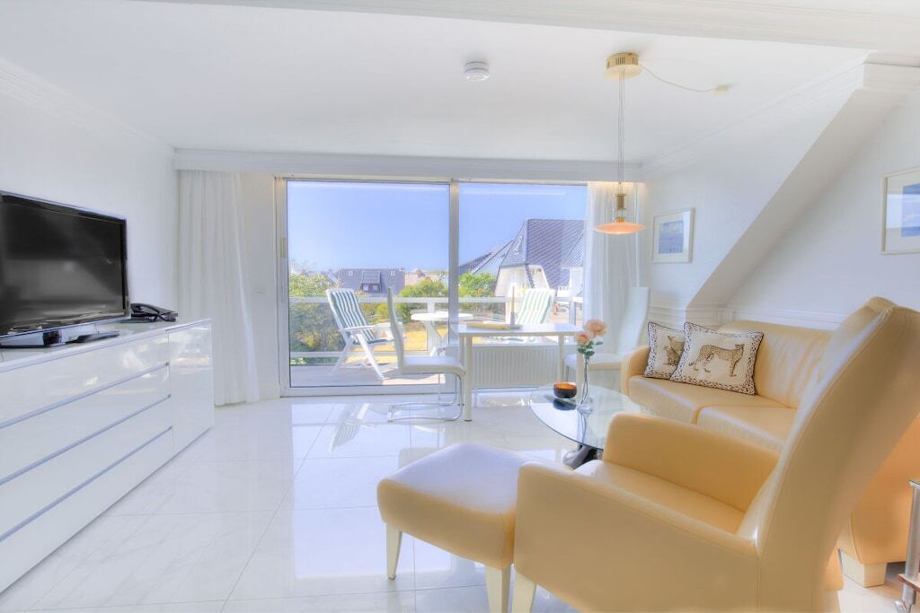 A modern living room with a flat-screen TV, a sofa, and a dining area with a table and chairs.