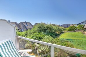 A balcony with a view of a green lawn and neighboring houses. - Holiday apartment in Sylt with 1 bedroom (Wenningstedt)