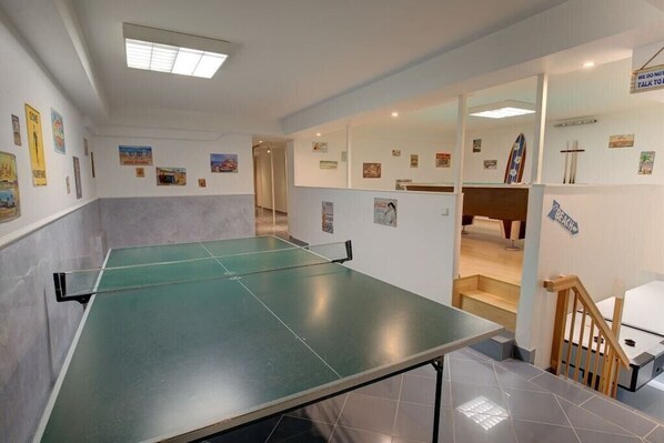 Une pièce équipée d’une table de ping-pong, d’un escalier et de divers éléments de décoration murale.