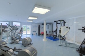 Une salle de sport équipée de machines de cardio, de matériel de musculation et d’un sac de frappe.