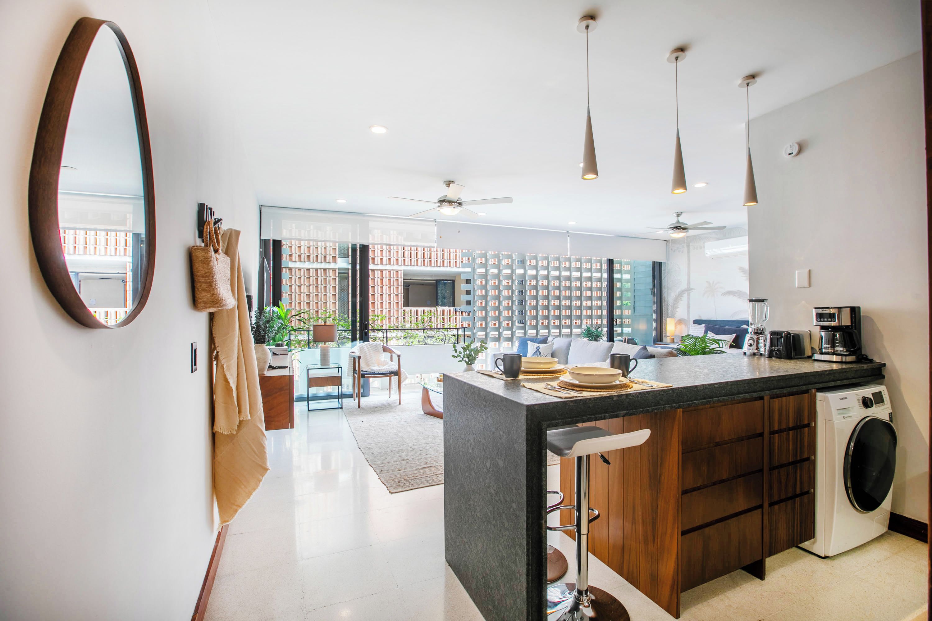 A modern kitchen with a central island, built-in appliances, and a view to a balcony with a brick wall.