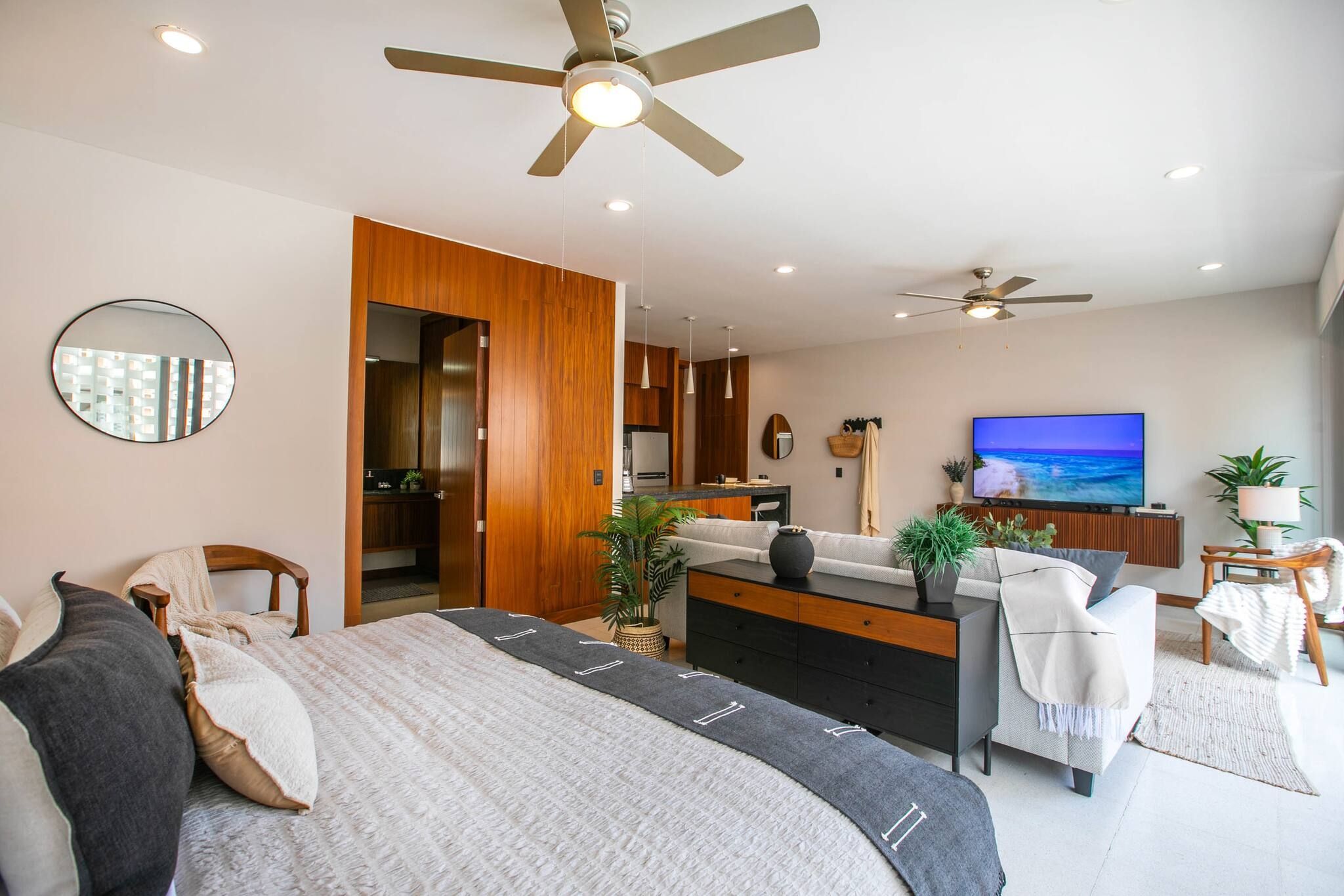 A modern bedroom with a large bed, a desk, and a TV.