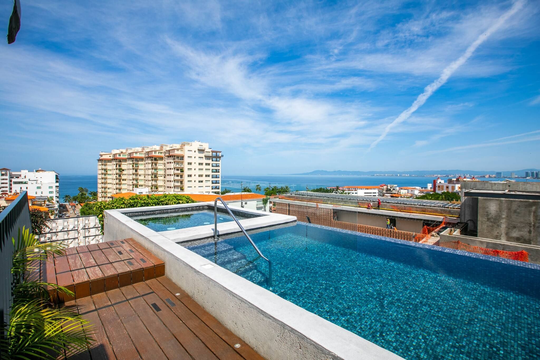Une piscine sur le toit offrant une vue sur l’océan et le paysage urbain.