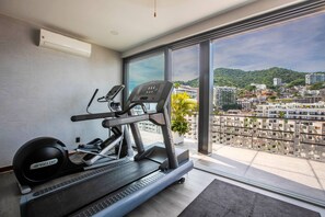 A gym with a treadmill and weights, large windows with a city view. - Infinity Pool & Hot Tub | Romantic Zone Hideaway (Puerto Vallarta)